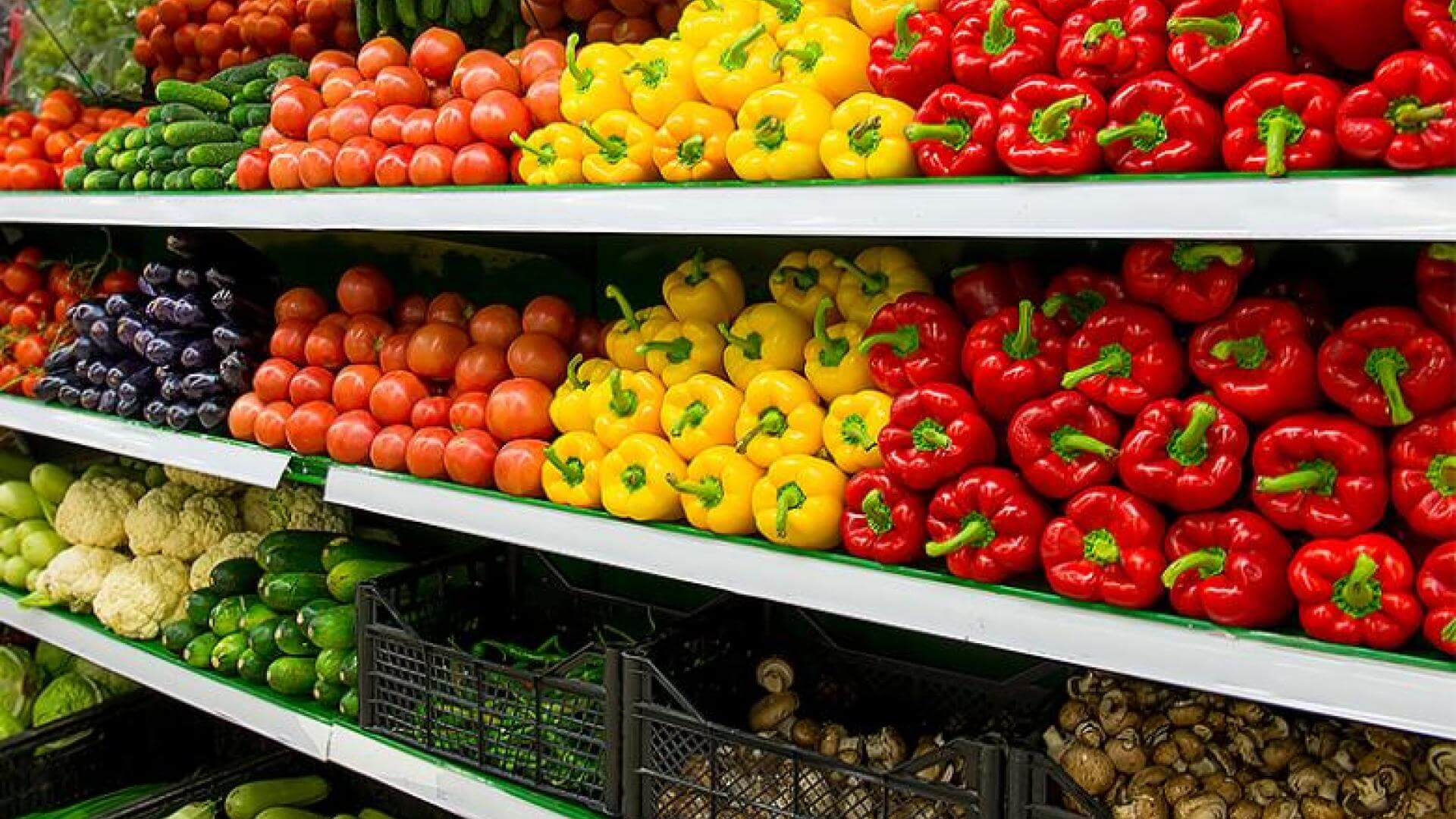 Rows of colorful fruits and vegetables at a grocery store.