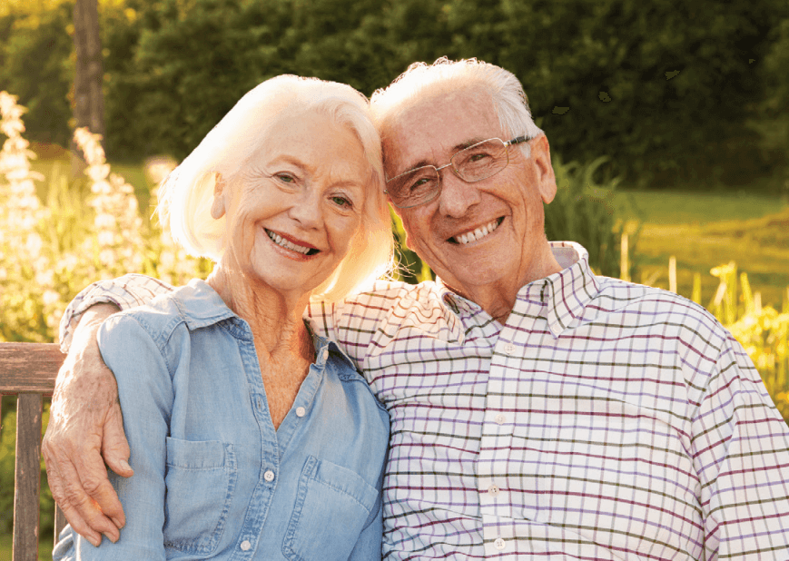 Senior couple sitting outside smiling. 