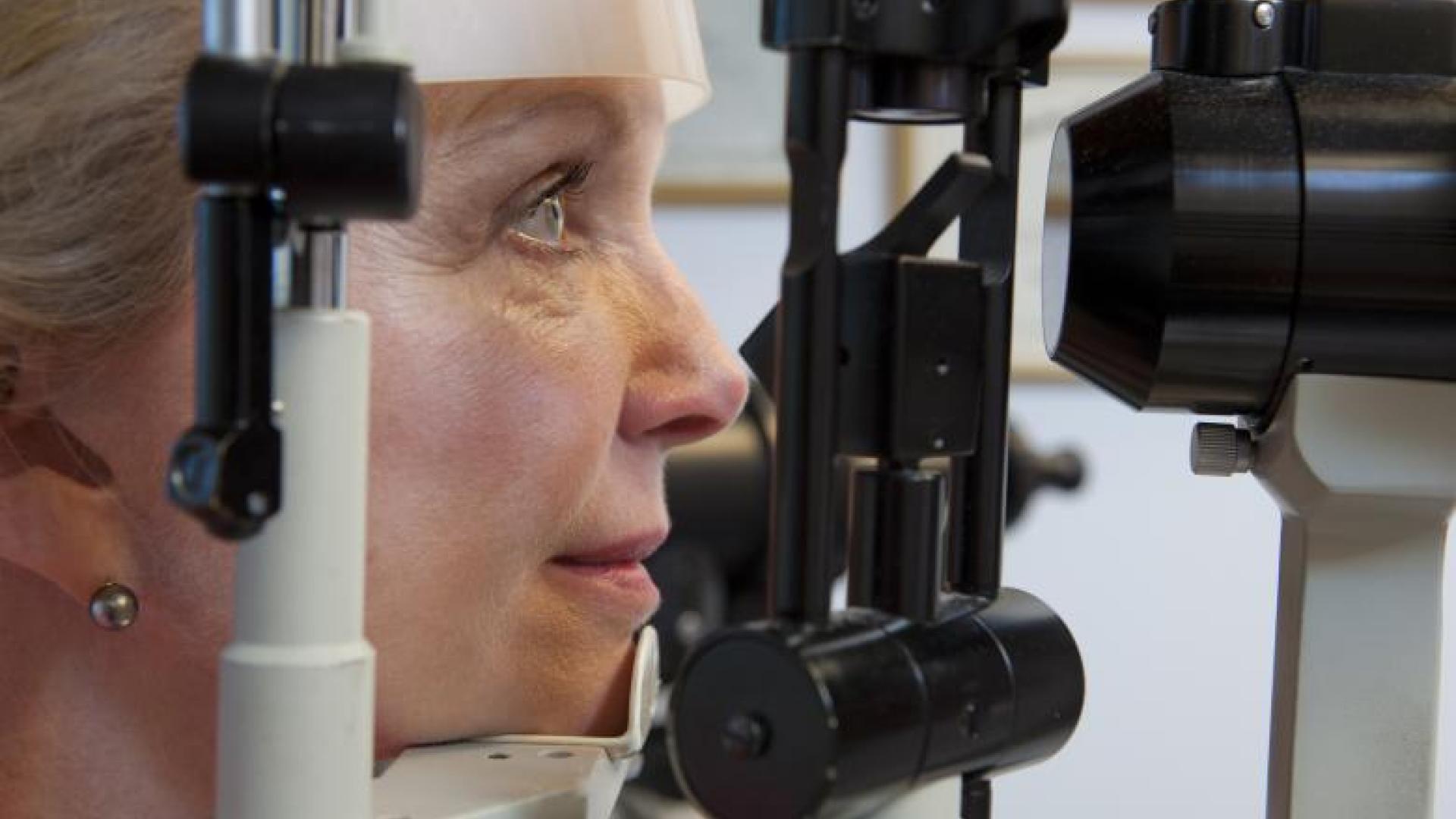 an older woman resting her chin on eye exam equipment