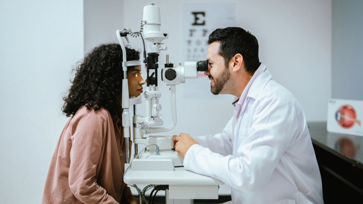 An eye doctor conducts an eye examination on a patient using a slit lamp in a clinic.