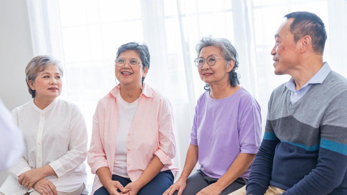 A row of four people sitting on a bench.