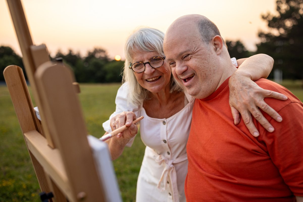 Man with Down syndrome paints in a meadow