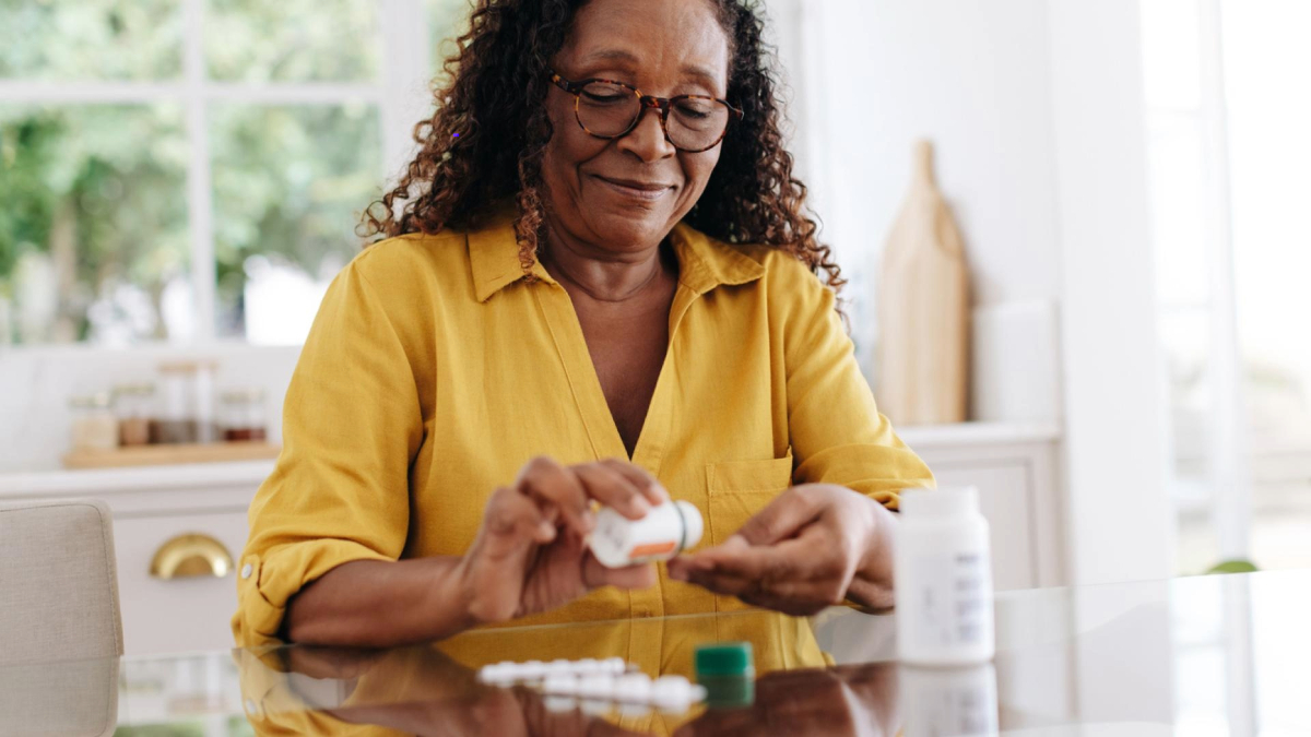 Person sorting medication into a pill organizer at a table.