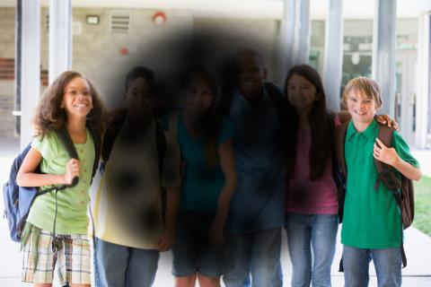 Children standing side by side with the a circular region of the photo blurred and blackened out.