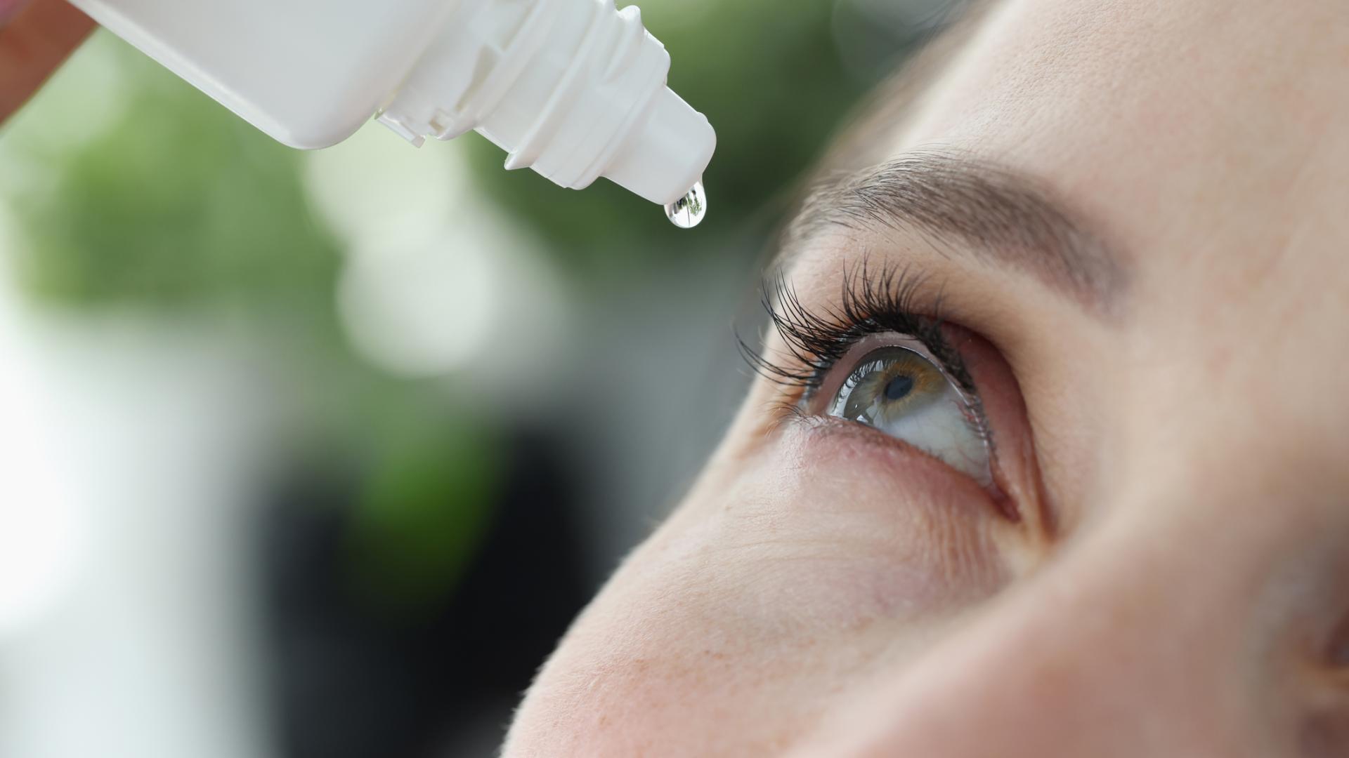 Close up photo of a woman adding eye drops to her own eye.