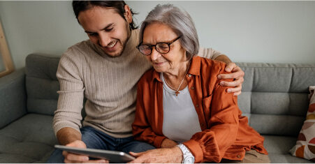 Son with senior mother looking at a tablet.