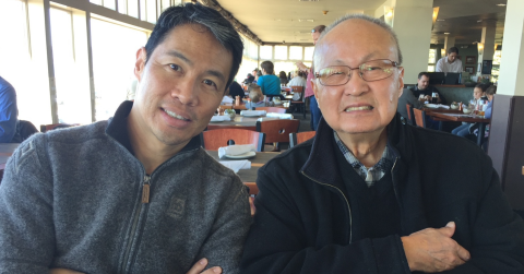 Richard Lui sitting for a photo with his father in a restaurant.