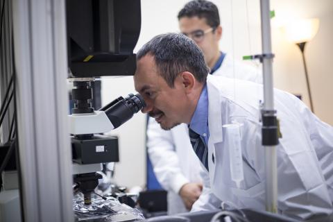 Dr. Albert Gonzales looking through a microscope.