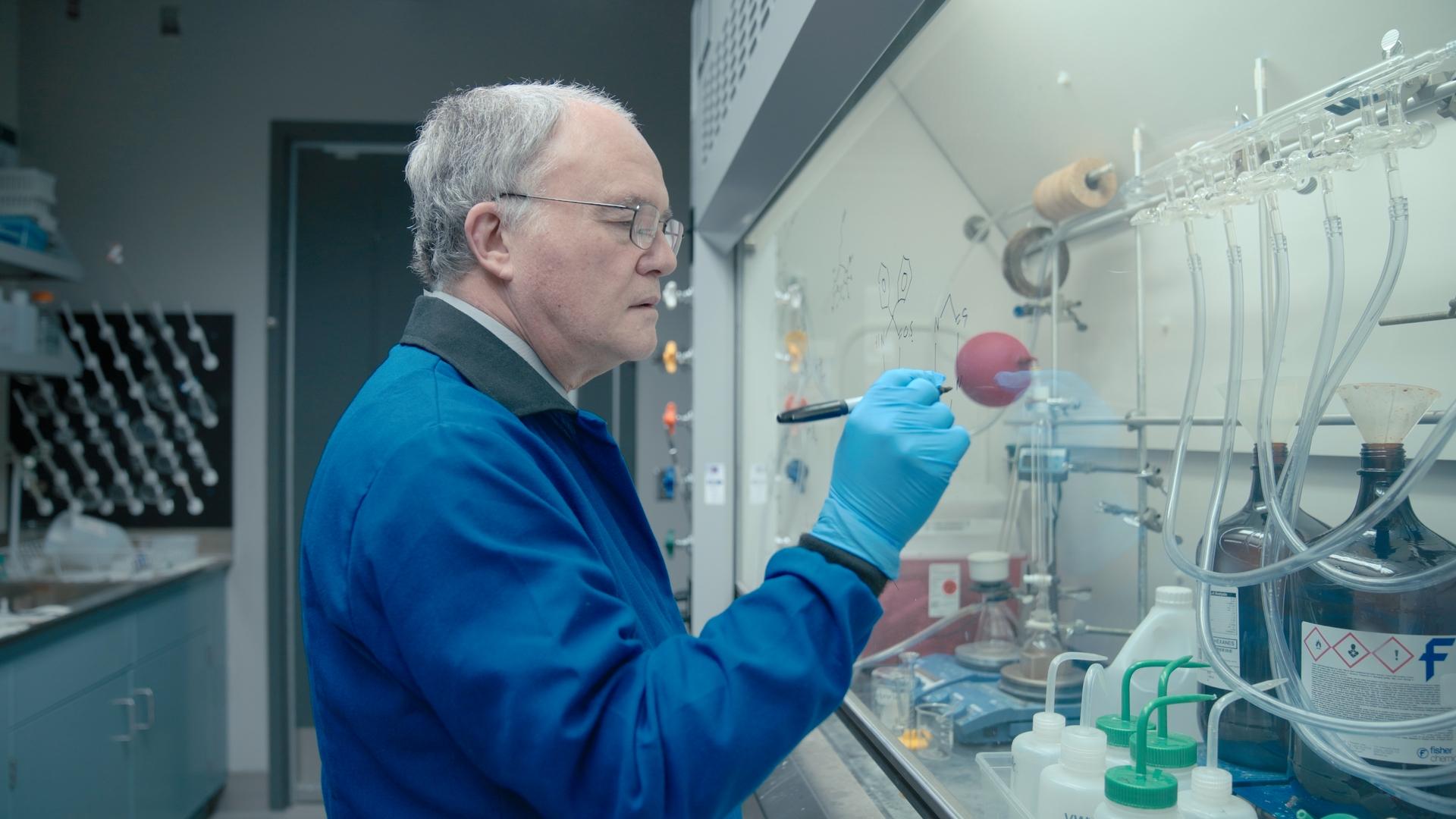 Donald Weaver, MD, PhD writing on the glass of the fume hood in his lab.