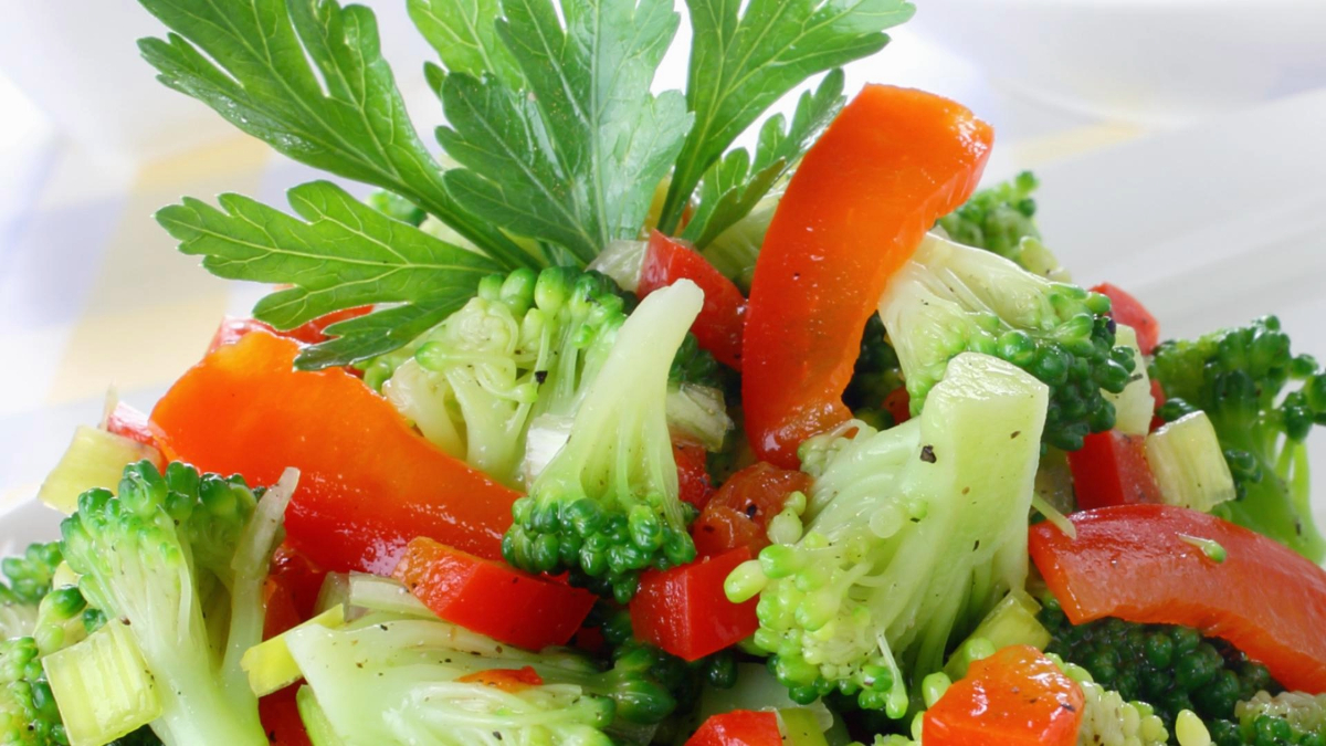 Bright and colorful close-up image of Marinated Broccoli Salad, a fresh vegetable salad consisting of broccoli and red bell pepper.