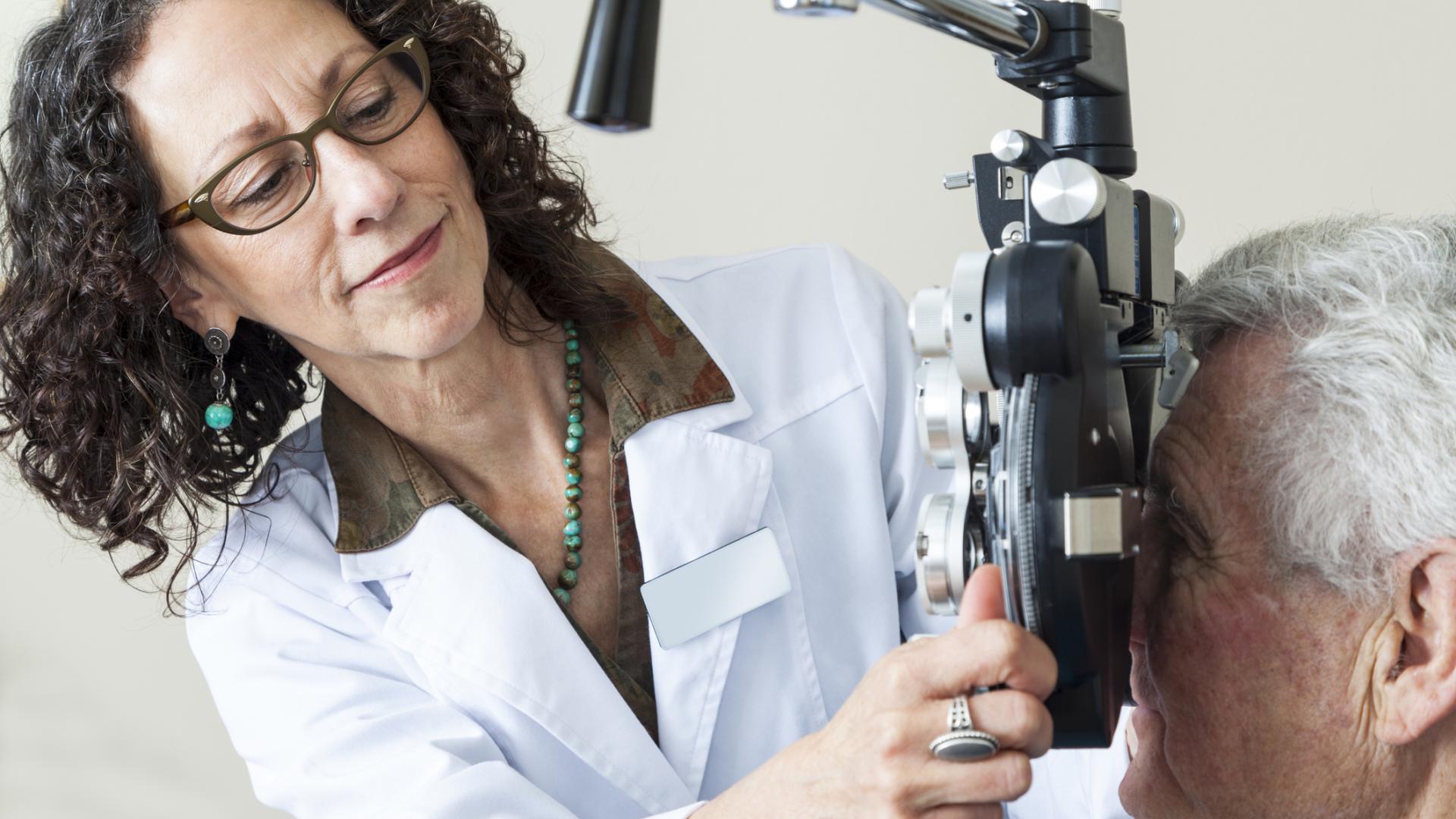 Optometrist giving eye exam to senior patient.