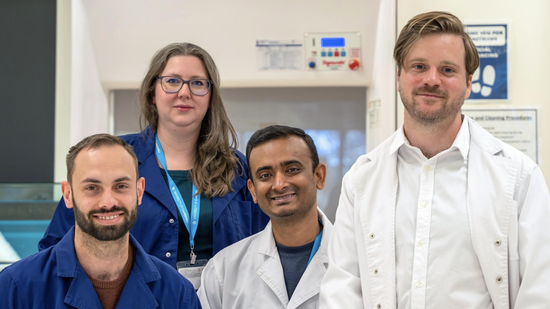 Four scientists in a group photo wearing their lab coats.