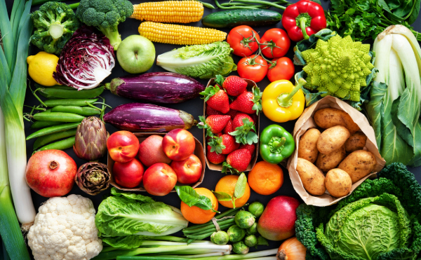 A vibrant, colorful assortment of fresh vegetables and fruits, including broccoli, corn, peppers, strawberries, and potatoes, arranged neatly to showcase a variety of textures and hues.