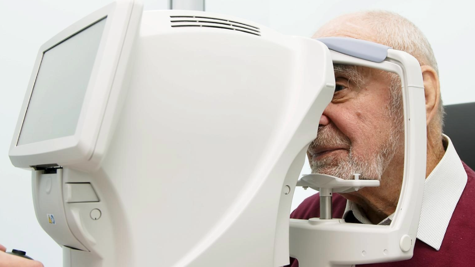 An elderly individual undergoing an eye examination using a modern retinal imaging machine.