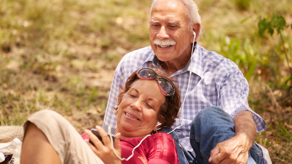 Senior couple listening to music in the park.