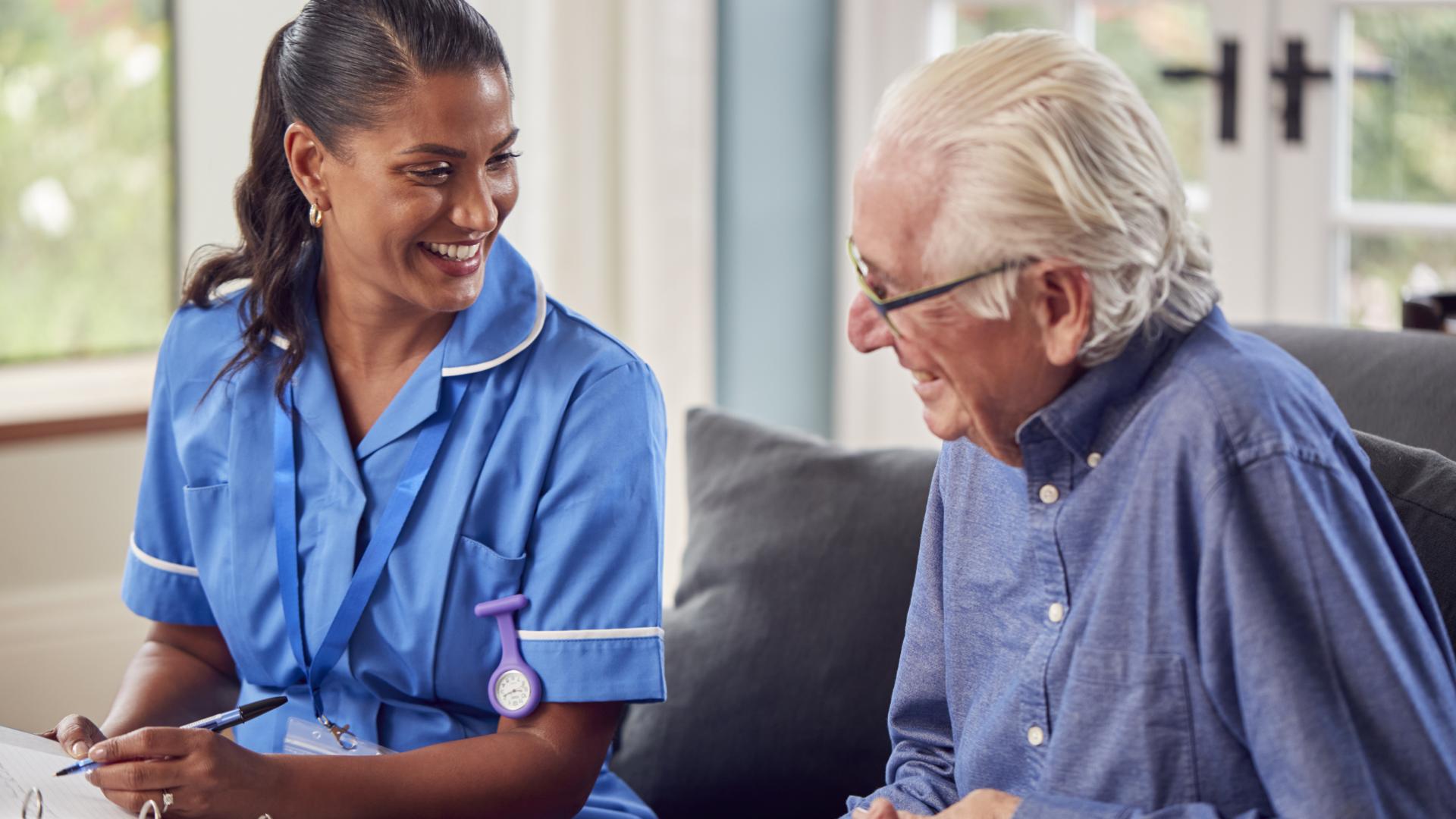 a dark-skinned woman wearing scrubs and a light-skinned man in a button-up shirt reviewing notes together