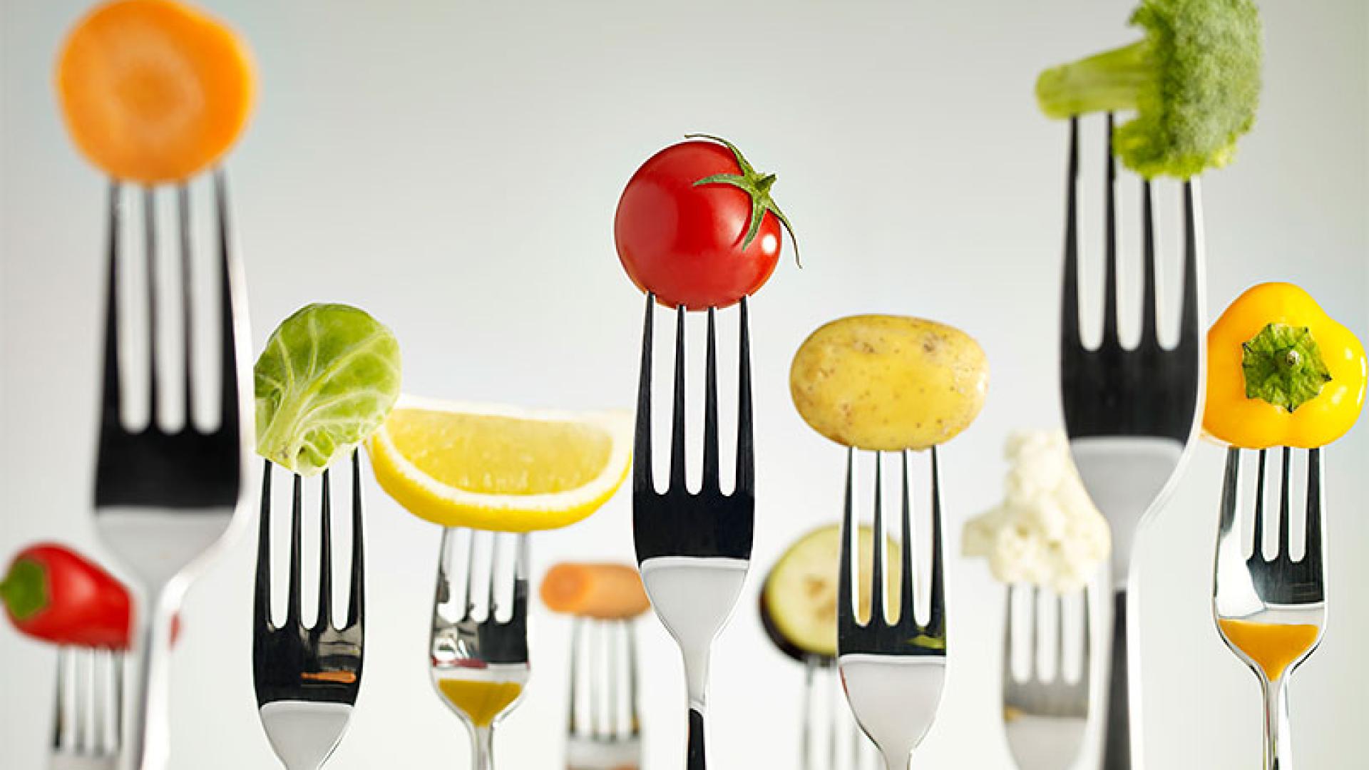 A variety of fruits and vegetables displayed on forks.