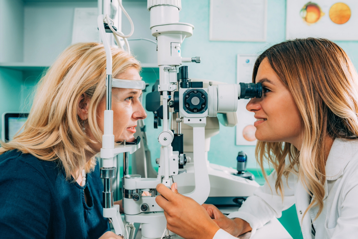 An ophthalmologist using specialized equipment to check a patient's eye health in a clinic.