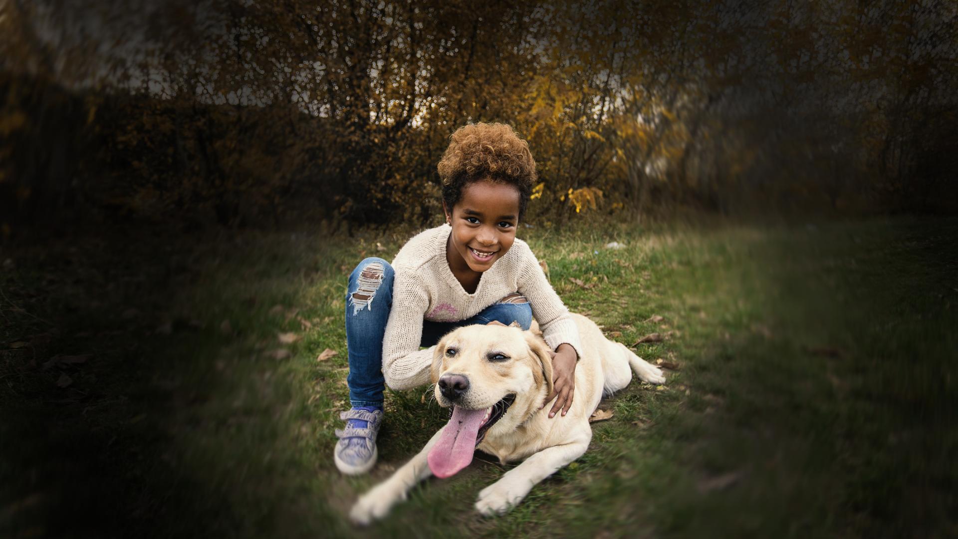 a child and a dog on a grassy lawn together. The outer edges of the photos are dark, meant to simulate vision with glaucoma