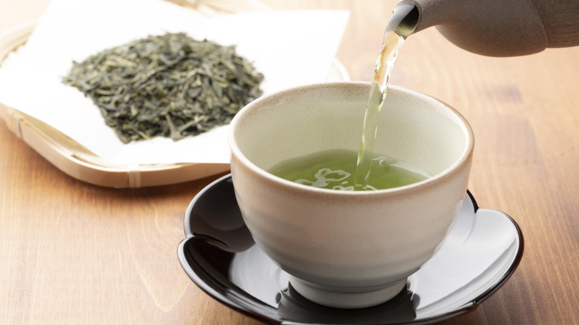 Green tea being poured into a tea cup.