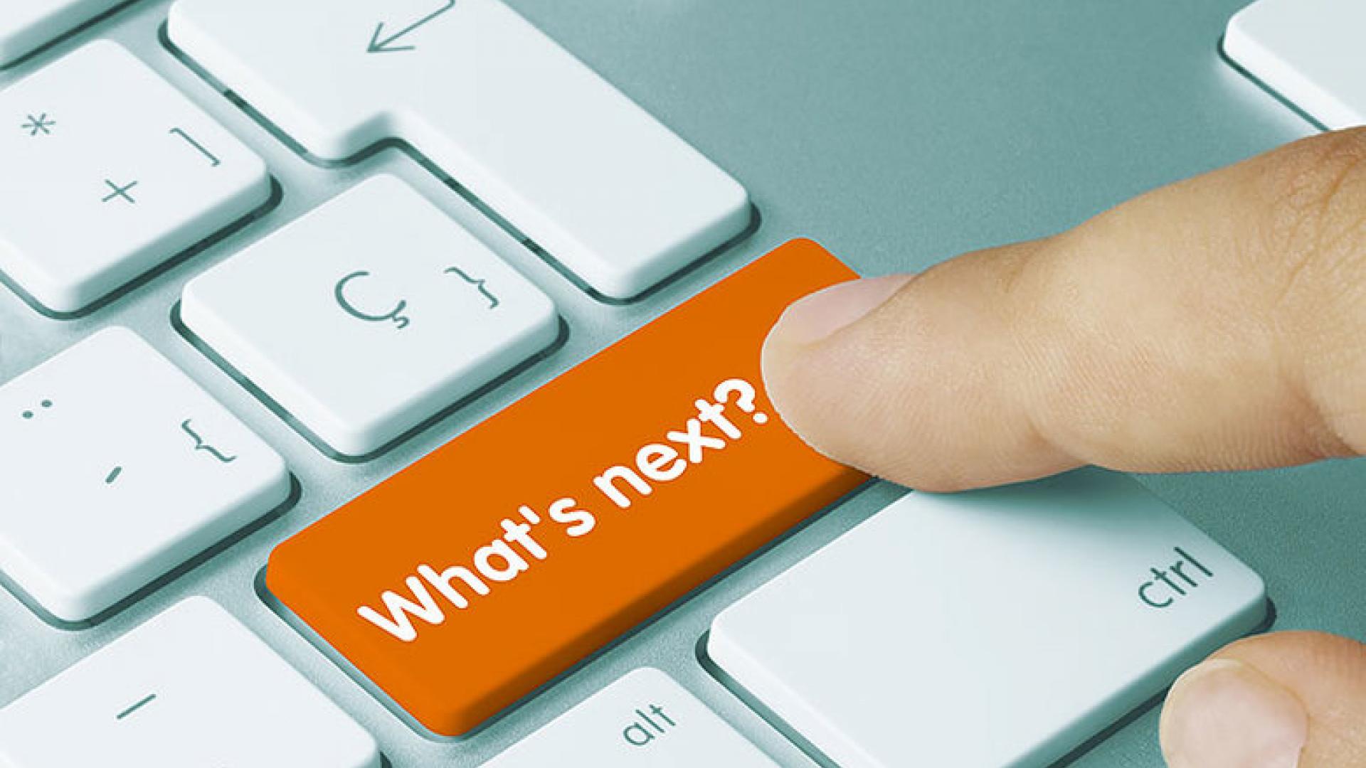 a close=up image of a finger hovering over an orange keyboard button that reads "WHAT'S NEXT?"