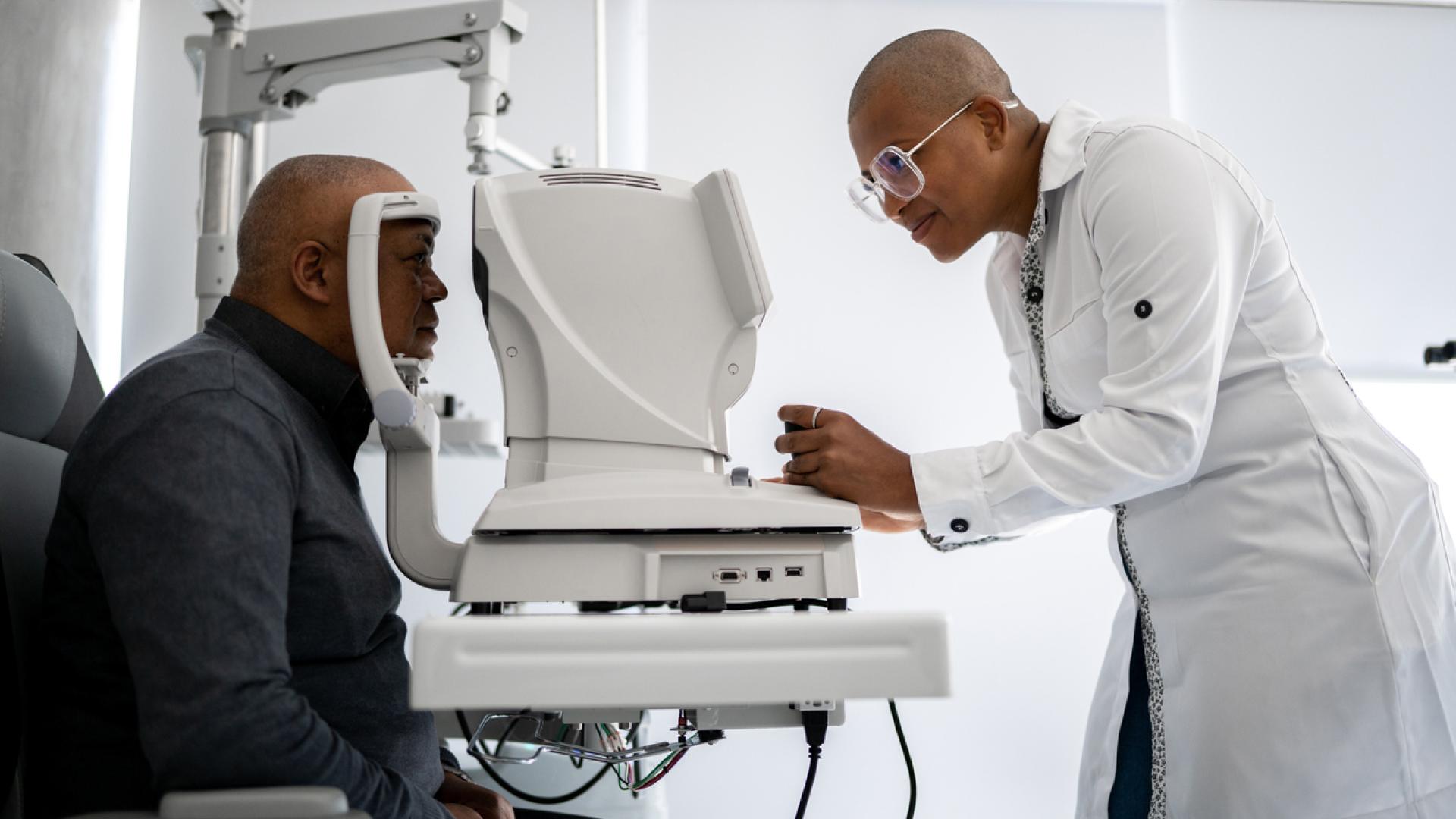 an African-American eye doctor performs an exam on an African-American man