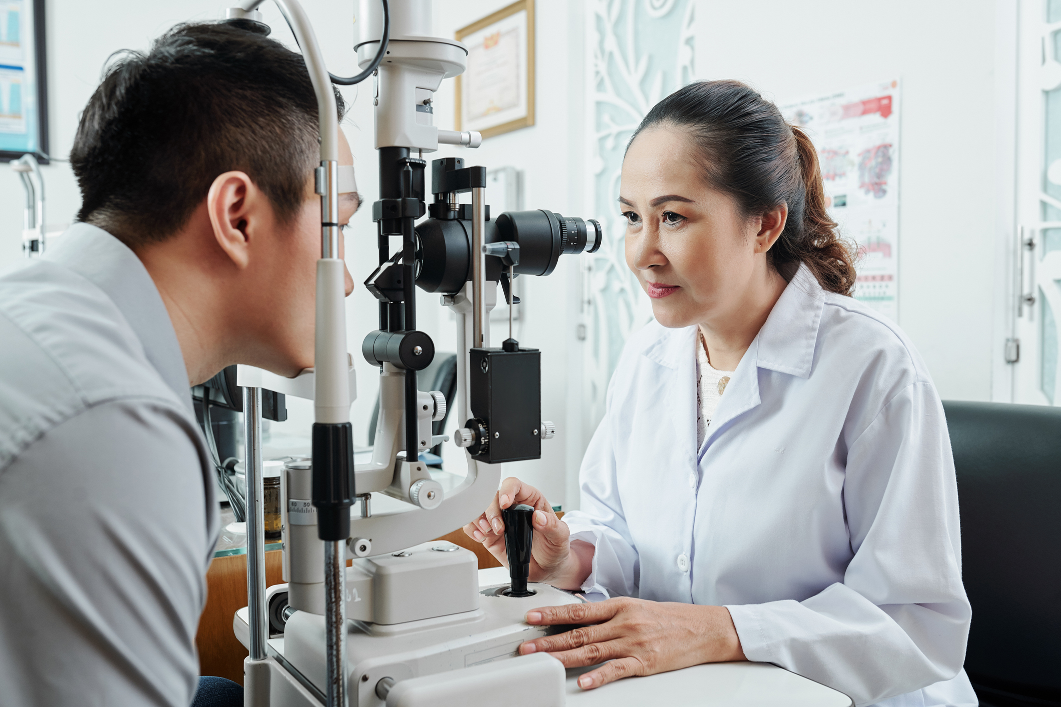 Man having eye exam with female doctor using slit lamp.