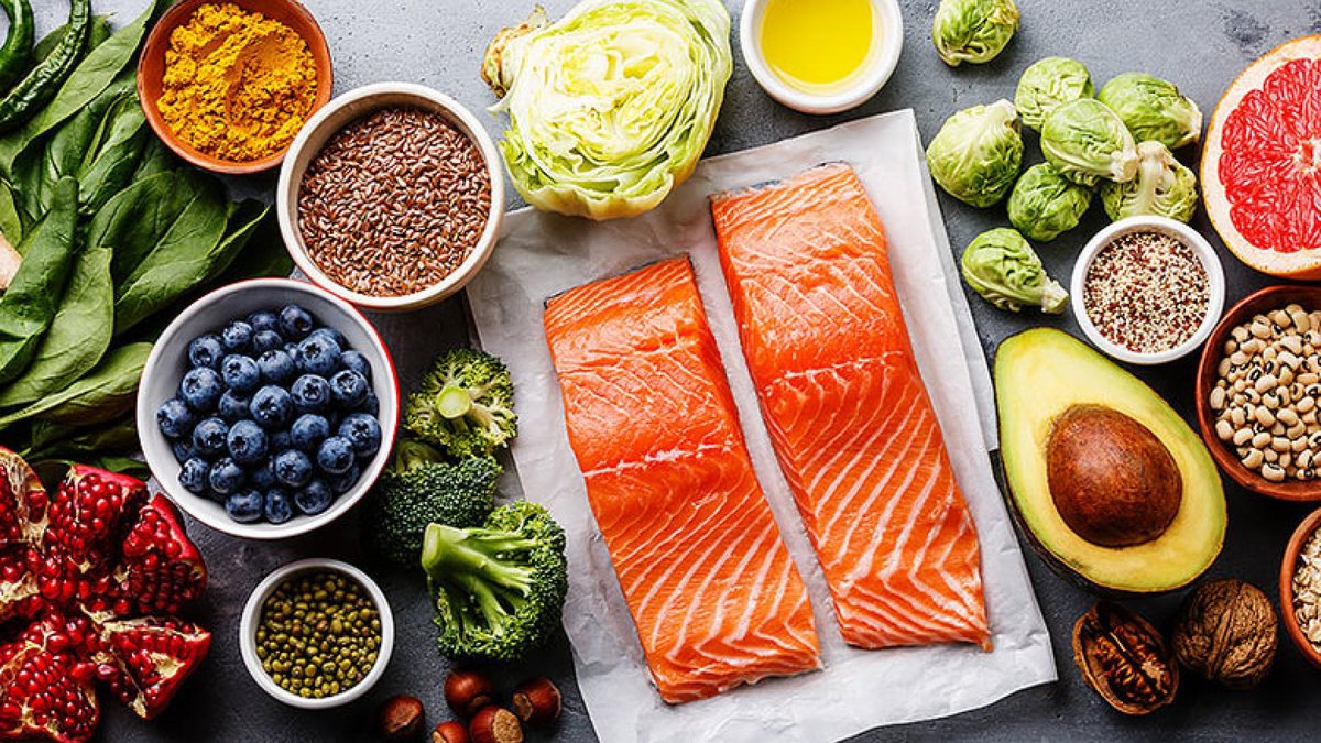 A selection of healthy foods for brain health, including salmon fillets, blueberries, spinach, avocado, flaxseeds, turmeric, and leafy greens, arranged neatly on a surface.