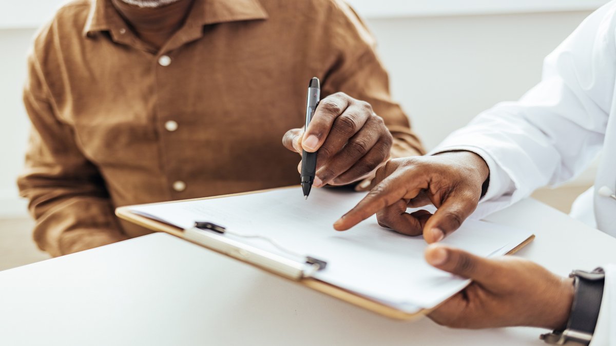 Hands hovering over a clipboard holding a pen.