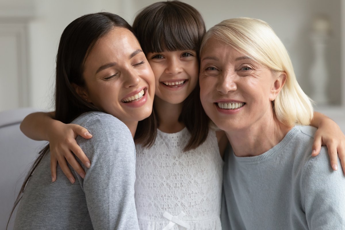 Laughing 3 generations of women family sitting together on sofa.