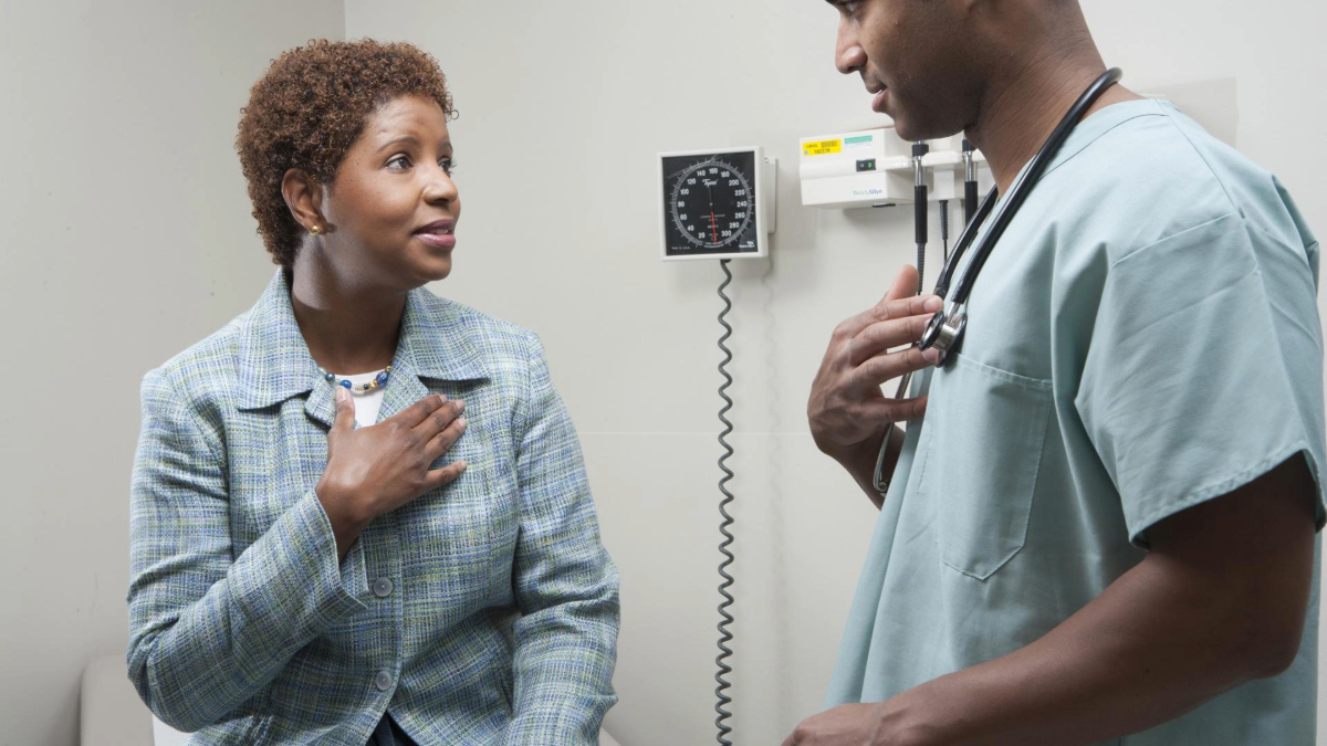 Patient wearing a blue shirt talking with her doctor.