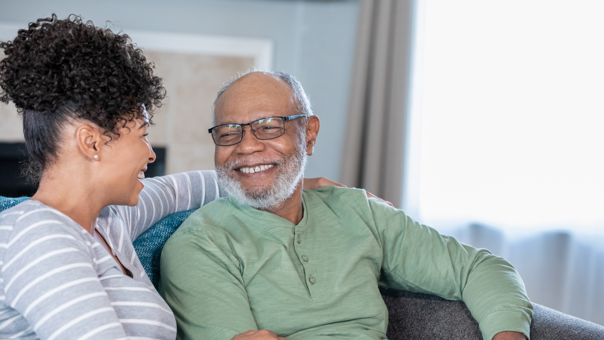 Adult daughter happily sitting with her elderly father.