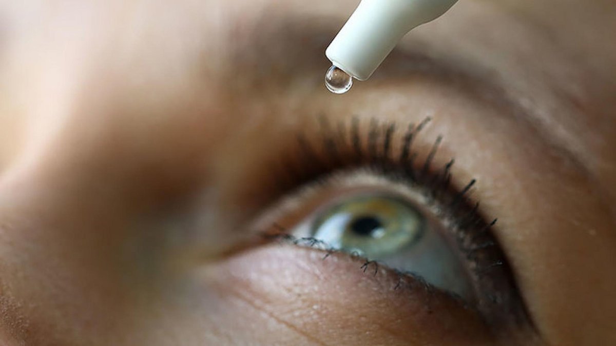 A close-up image of a person’s eye with a drop of liquid falling from an eye dropper, suggesting the use of eye drops for conditions like glaucoma.