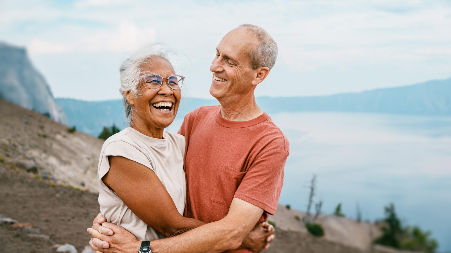 Senior couple outdoors laughing and embracing.