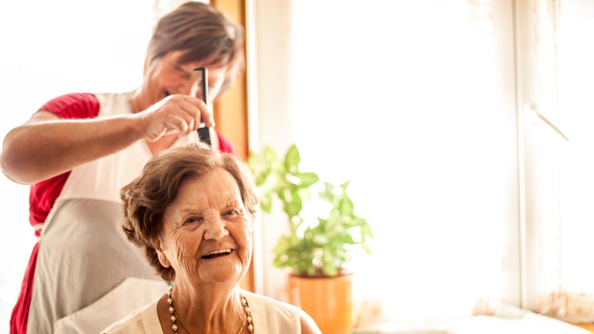 Senior woman gets her hair brushed by a loved one.