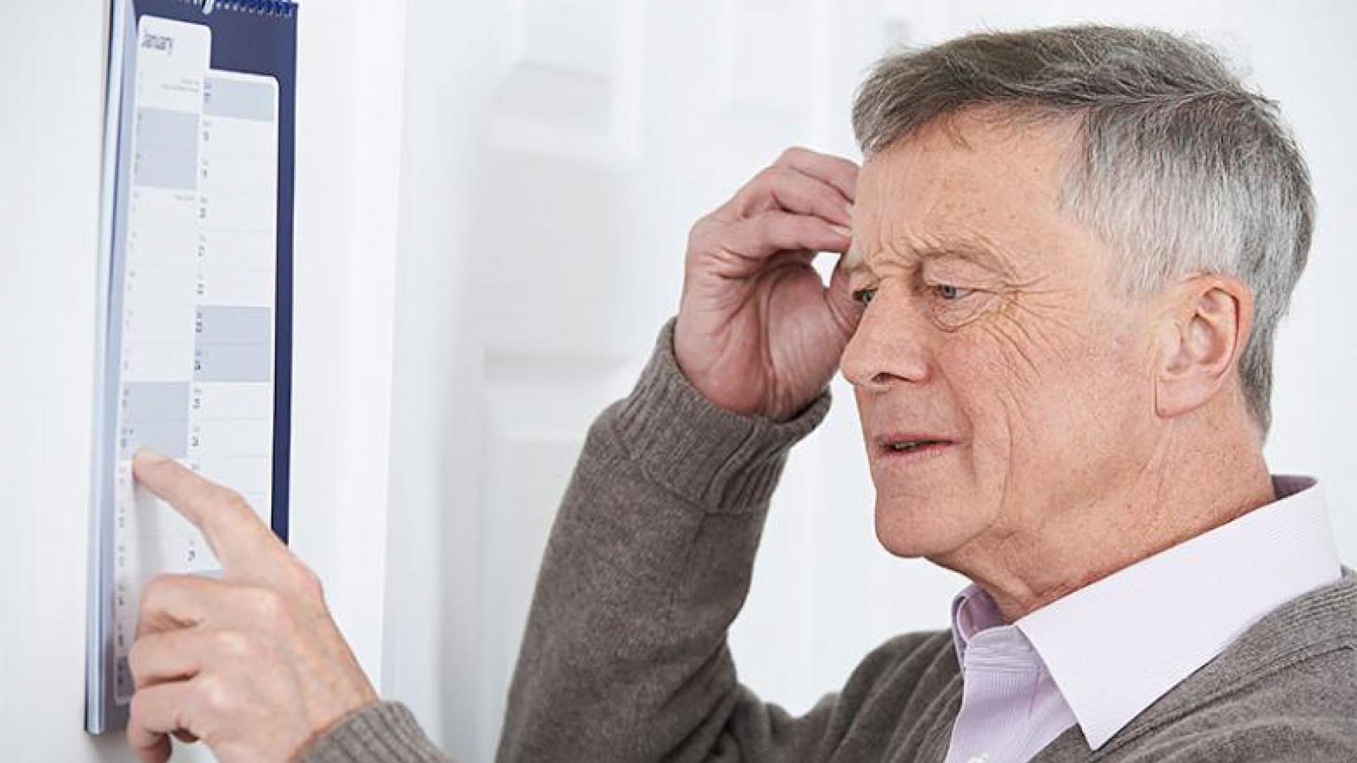 an elderly man stares at a piece of paper, clearly confused