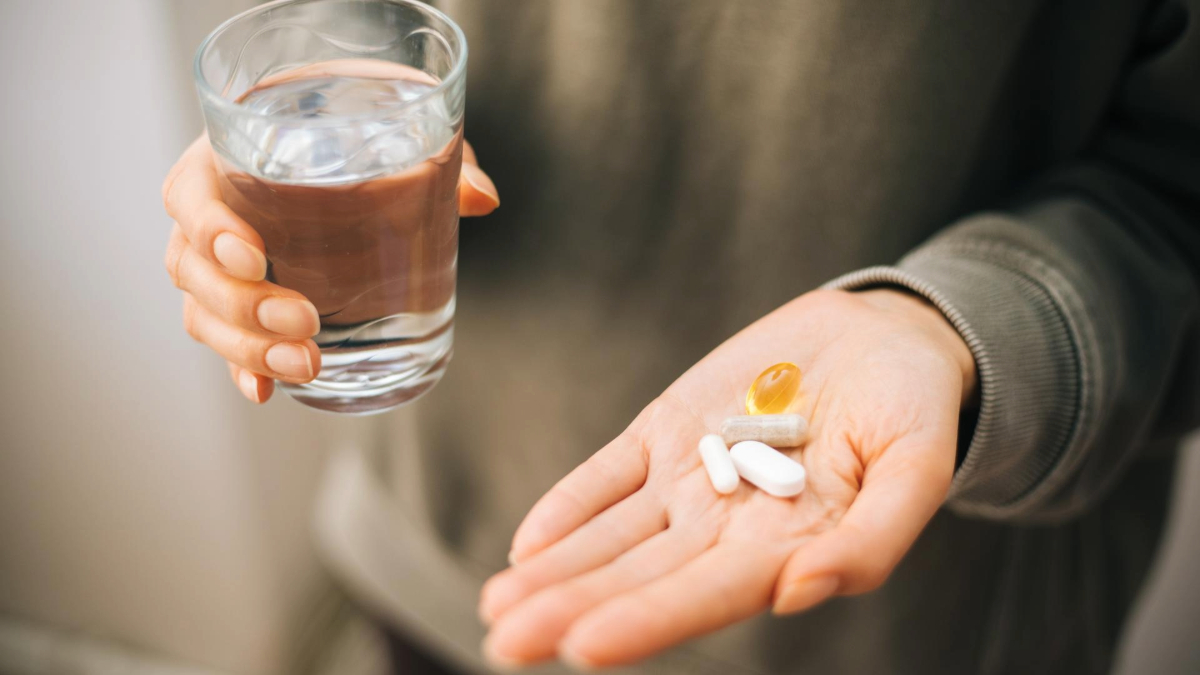 Person holding water and vitamins.