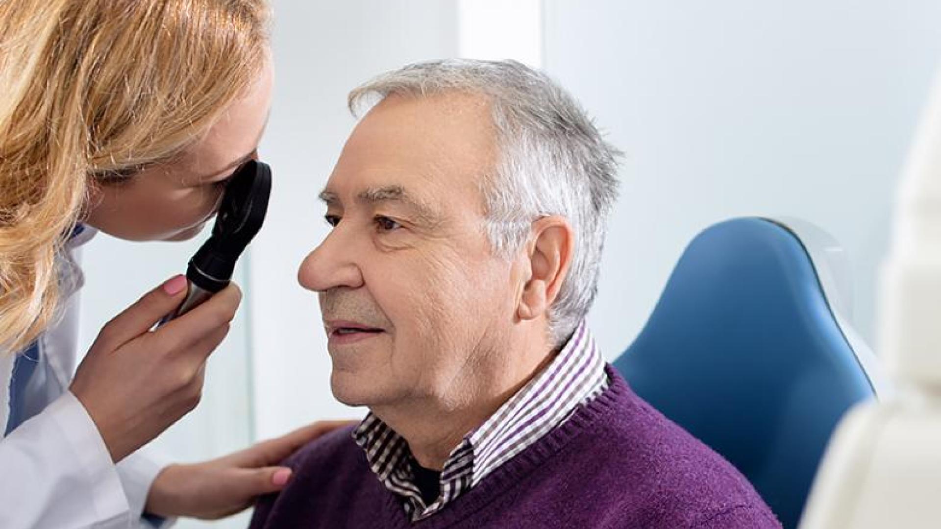 A woman eye doctor examining a senior male patient.