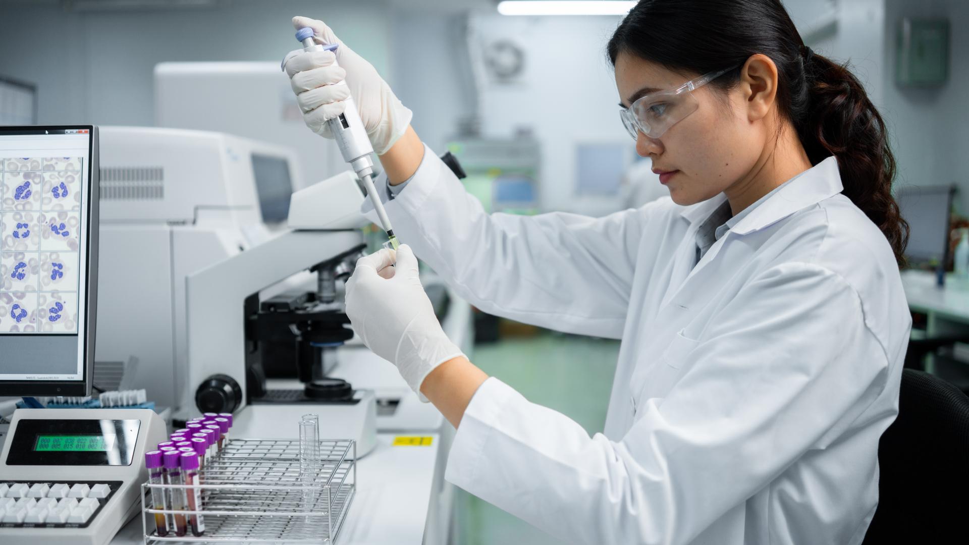 Woman scientist holding a pipette in a lab.