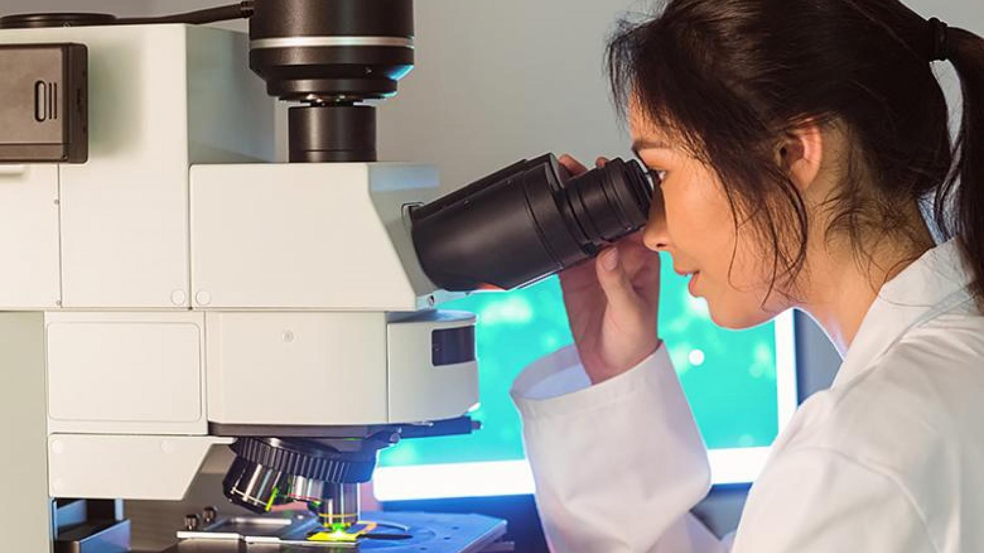 A female scientist looking through a microscope.