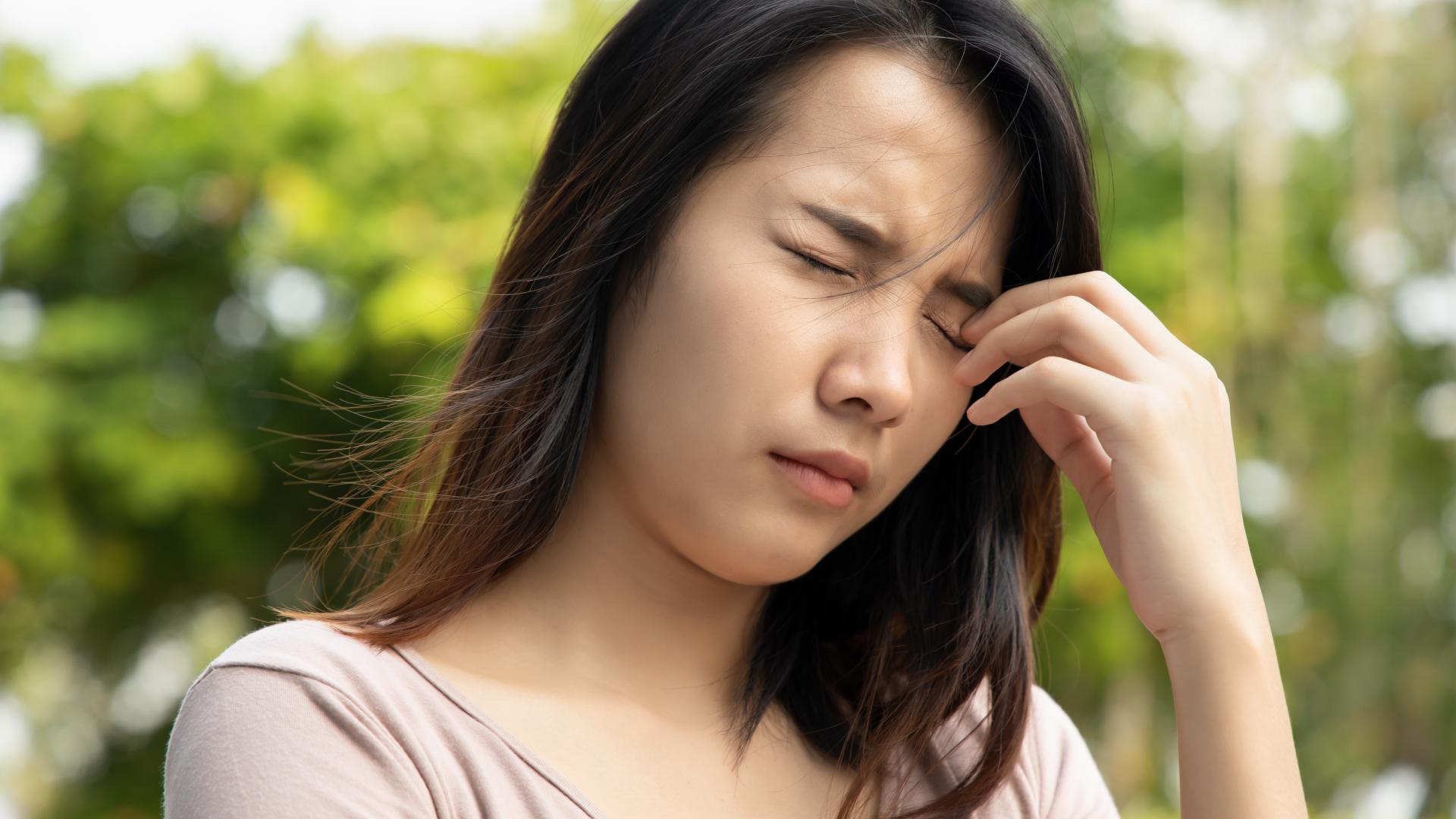 A woman with her eyes closed due to visual symptoms.