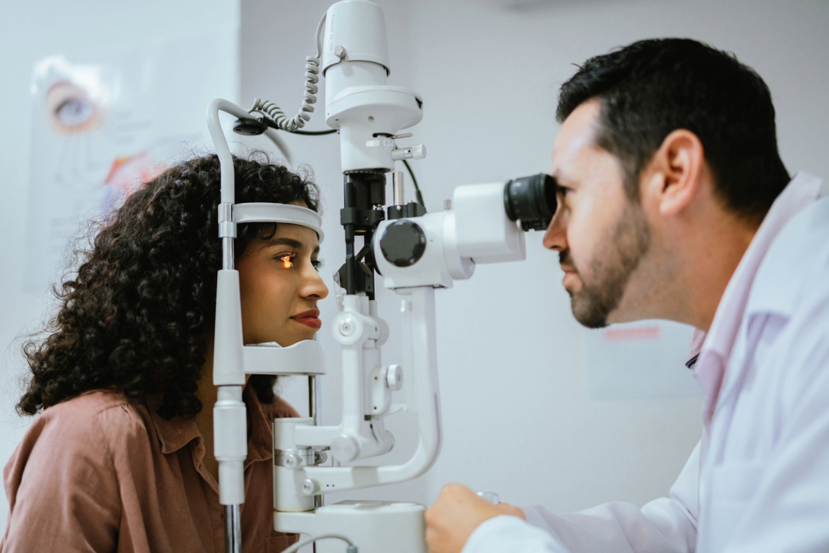 An optometrist using an eye examination machine to check a patient's vision in a clinic.