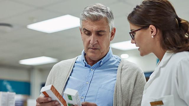 A doctor and a patient look at a box of medicine together.