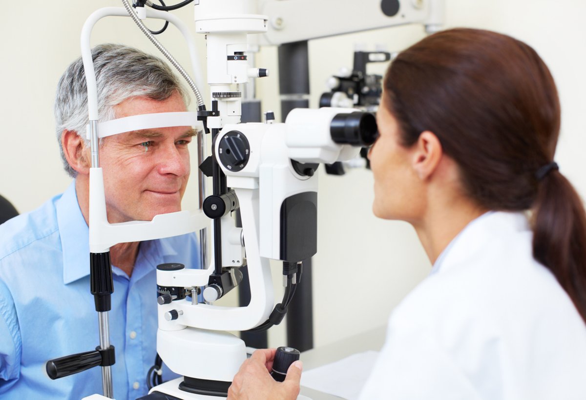 An ophthalmologist conducting an eye examination using a slit lamp machine on a male patient.