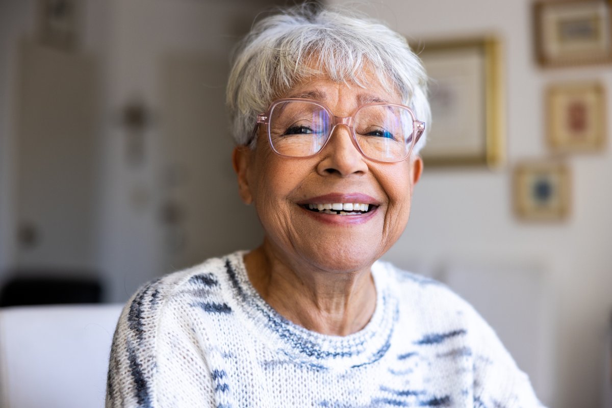 Senior woman with short gray hair and glasses smiling warmly.