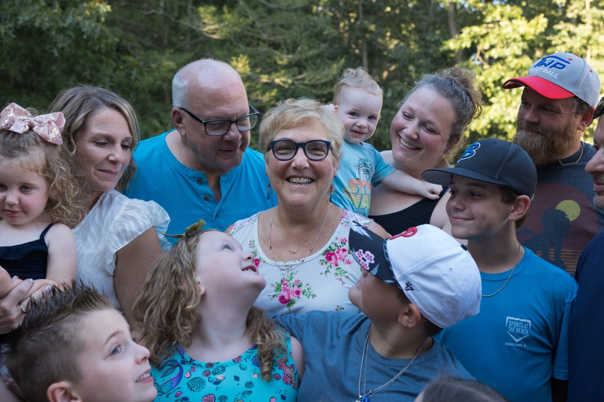 A family stands together smiling outdoors.