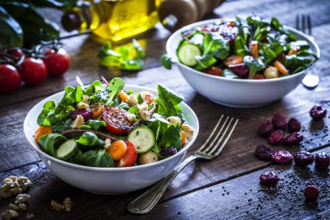 Two bowls of salad on a table top.