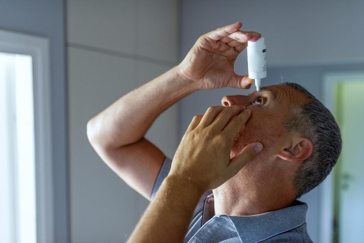 Man using eye drops for glaucoma.