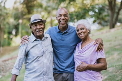 A multigenerational family smiles outdoors.