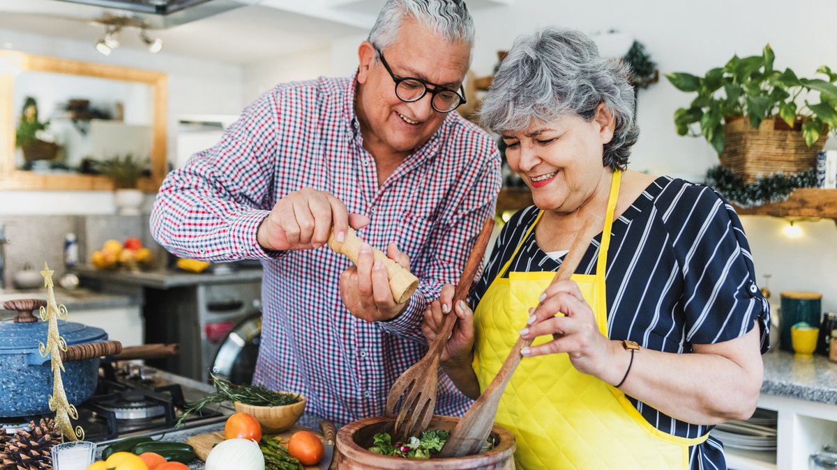 Elderly couple happily cooks together in the kitchen.